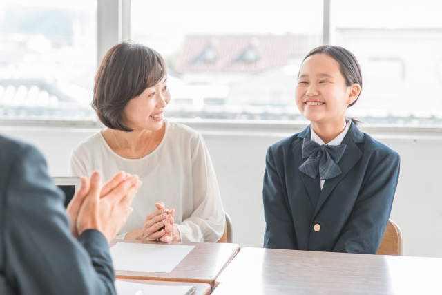 三者面談で笑顔の女子中学生とそれを見る母親