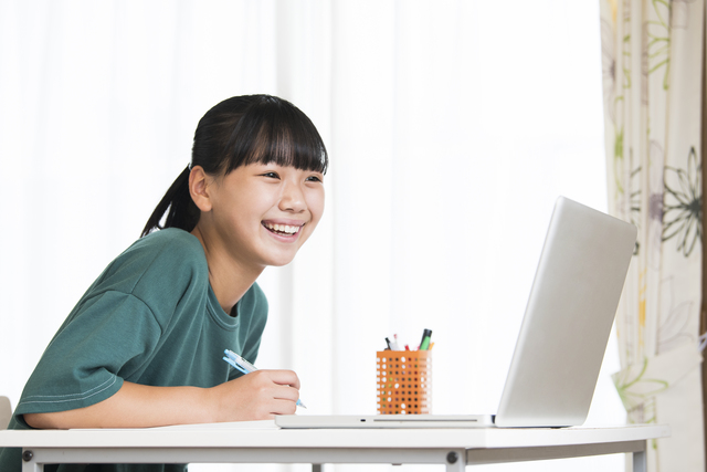 楽しそうにPCに向かってペンを持つ女子中学生